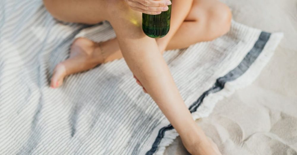 Beer - Person Sitting on the Sand Holding a Green Glass Bottle