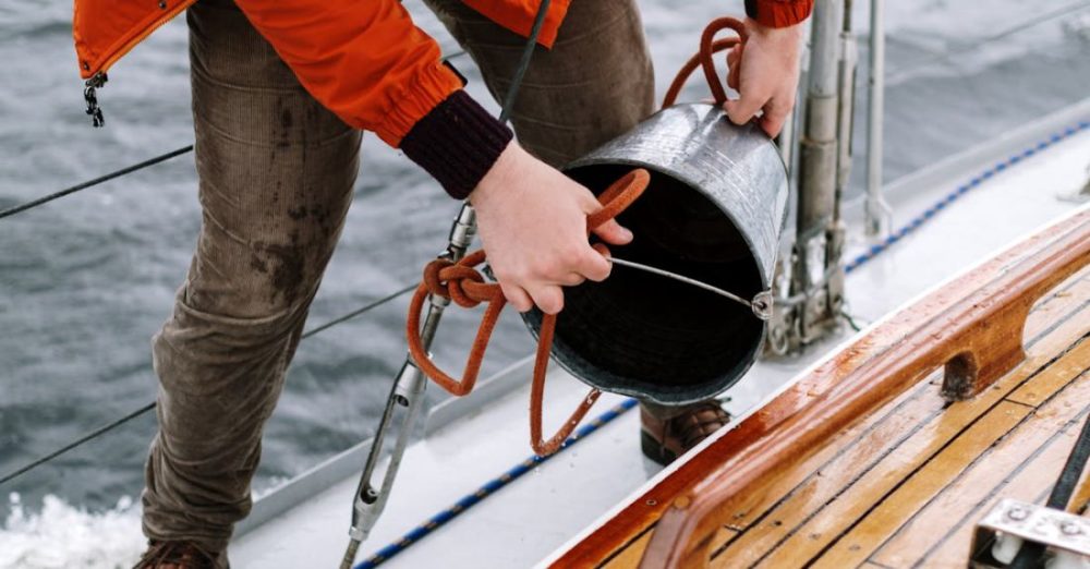 Fishing - Man in Orange Jacket and Gray Pants Holding Black and Red Fishing Rod