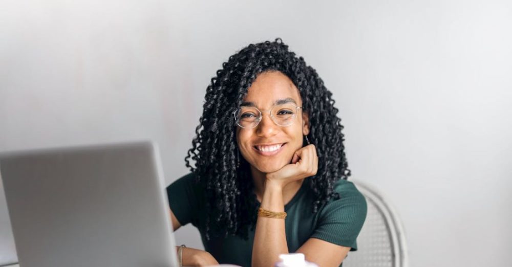 Study Spaces - Happy ethnic woman sitting at table with laptop